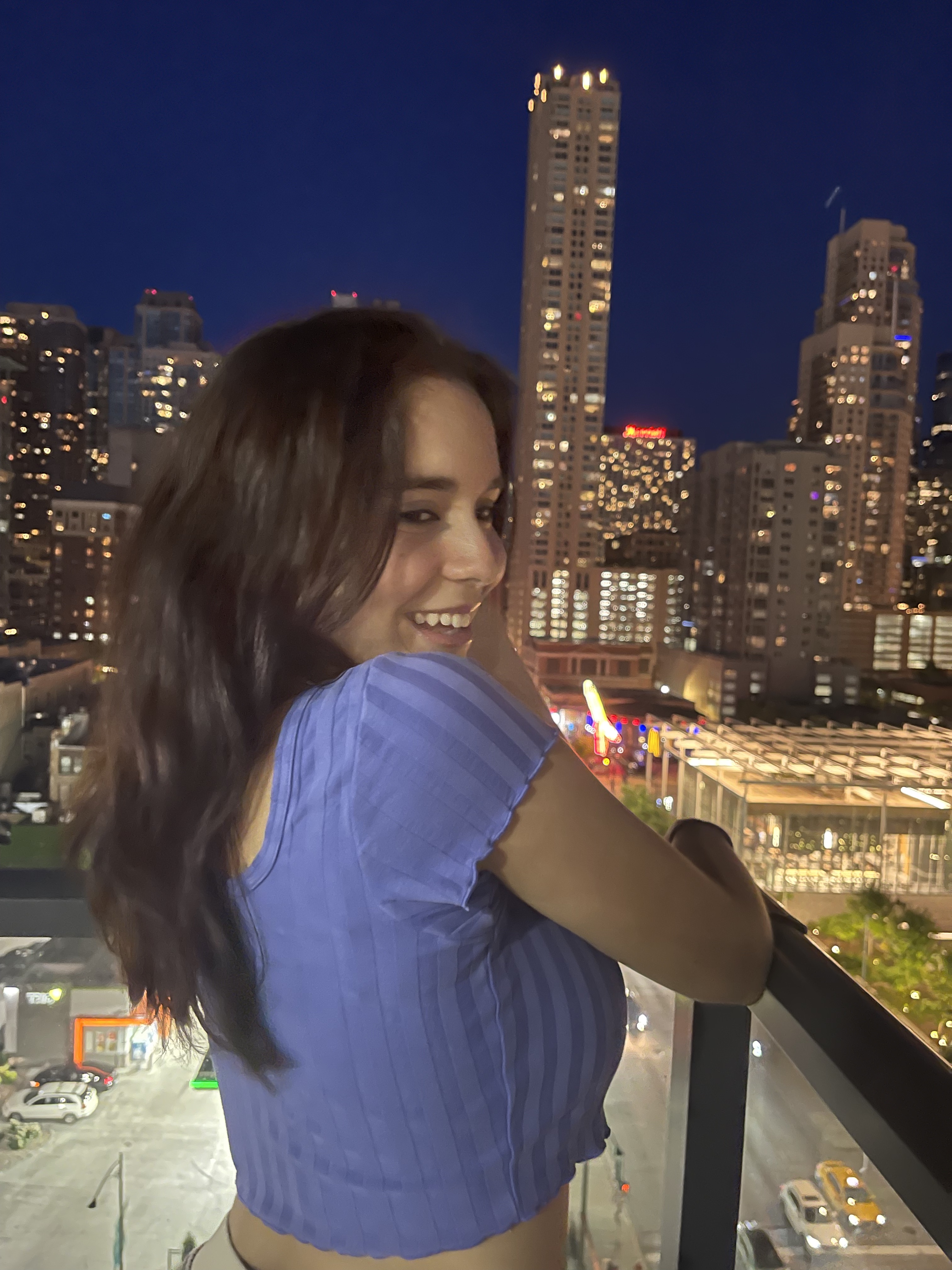 Photo of Nicole on balcony with city skyline in background